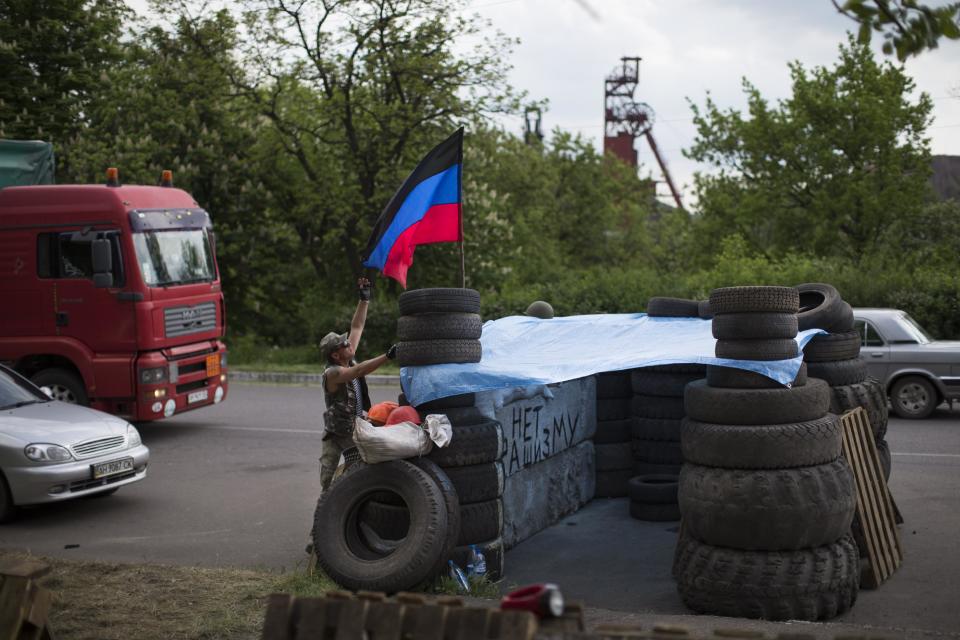 Pro-Russian insurgents with the self-proclaimed Donetsk People's Republic man a checkpoint by the Karl Marx coal mine seen in the background near Korsun, a small town about 30 km north-east from Donetsk, eastern Ukraine, Tuesday, May 13, 2014. The words on the wall of barricades read " No fascism". The Donetsk People's Republic has proclaimed independence from Ukraine after a contentious autonomy referendum Sunday that has been rejected by the government and the international community. (AP Photo/Alexander Zemlianichenko)