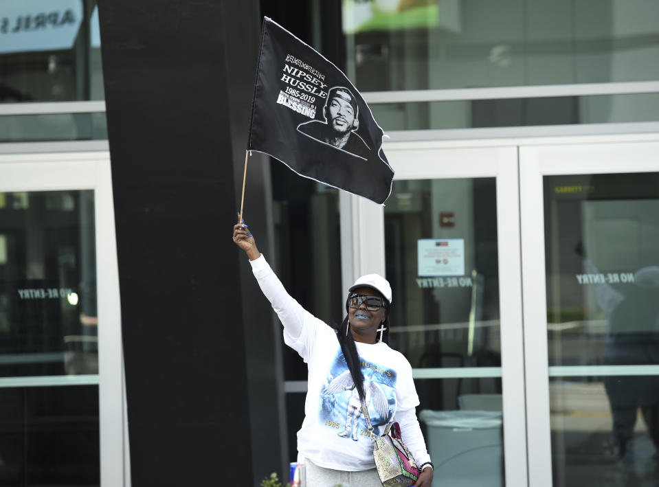 Michante Clark, of Sacramento, Calif., holds up a tribute flag at the Celebration of Life memorial service for late rapper Nipsey Hussle, whose given name was Ermias Asghedom, on Thursday, April 11, 2019, at the Staples Center in Los Angeles. (Photo by Chris Pizzello/Invision/AP)
