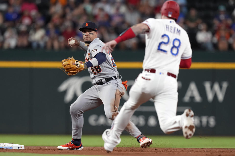 Detroit Tigers shortstop Javier Baez (28) tries to turn a double play as Texas Rangers' Jonah Heim comes into second base allowing teammate to Robbie Grossman to reach first base safely during the second inning of a baseball game in Arlington, Texas, Tuesday, June 27, 2023. (AP Photo/LM Otero)