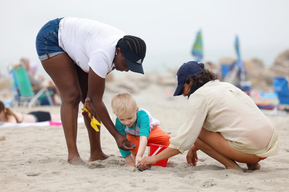 Langston Flynn, center, plays in the sand with two volunteers at Roger Wheeler State Beach in Narragansett on Wednesday. The volunteers, current and former URI nursing students, hosted the beach day as part of their summer program of respite care for parents of special-needs children.