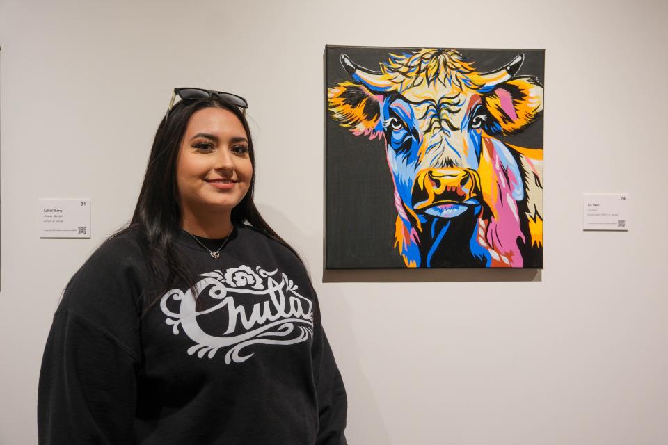 Liz Razo stands by her painting "La Vaca" at the 20x20 Art Exhibition and Silent Auction at the Amarillo Museum of Art on the campus of Amarillo College.