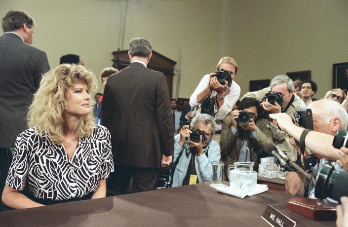 FILE - Fawn Hall, former secretary for fired National Security Council staff member Lt. Col. Oliver North, is surrounded by photographers during an appearance before the joint House-Senate Iran-Contra committees on Capitol Hill in Washington on June 8, 1987. Hall testified that she had helped North shred documents related to the Iran-Contra affair. (AP Photo/John Duricka, File)