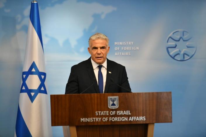 Israeli Foreign Minister Yair Lapid at a podium beside the Israeli flag, with Ministry of Foreign Affairs printed on the wall behind him.