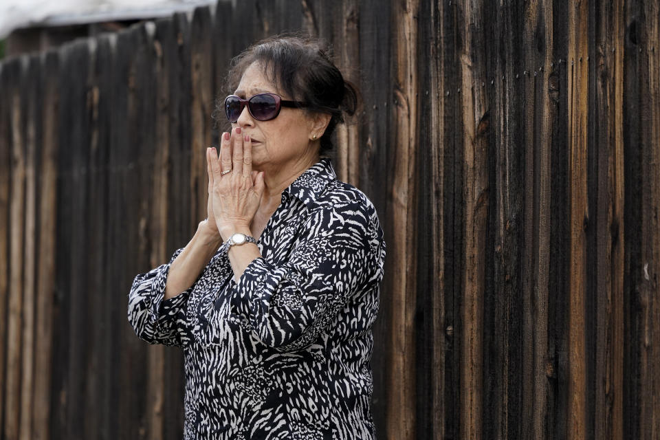 A neighbor watches fire crews near the scene of a small plane crash, Monday, Oct. 11, 2021, in Santee, Calif. At least two people were killed and two others were injured when the plane crashed into a suburban Southern California neighborhood, setting two homes ablaze, authorities said. (AP Photo/Gregory Bull)