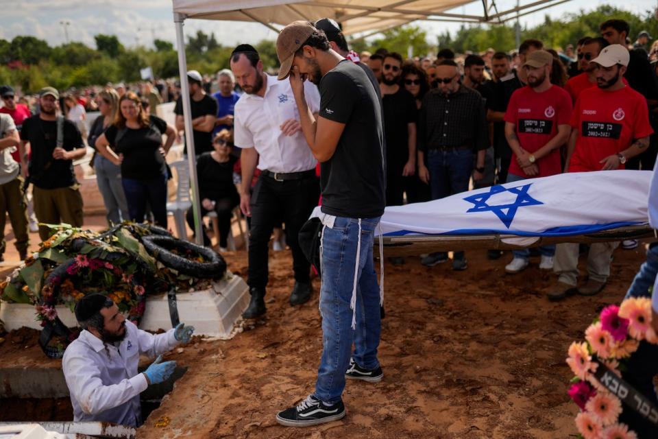 Covered with the Israeli flag, the body of Ben Fishman is buried at Pardes Haim cemetery in Kfar Saba, near Tel Aviv, Israel, Sunday, Oct. 15, 2023. Fishman was killed when Hamas unleashed its attack on thousands of Jews attending a music festival in southern Israel earlier this month.