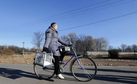 A member of an election commission carries a mobile election box as she cycles to collect votes from local residents during a parliamentary election, in Horodyshche near Chernihiv, October 26, 2014. REUTERS/Stringer