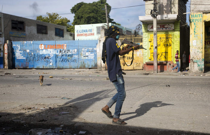 An armed civilian carries a weapon on during a shootout between rival gangs to take control of the Croix-des-Bossales market, on Boulevard Jean-Jacques Dessalines, a main commercial artery, in Port-au-Prince, Haiti, Wednesday, Nov. 21, 2018. The fight for control of the market, where vendors pay the controlling gang regular payments, erupted amid days of protests and a strike against alleged government corruption. (AP Photo/Dieu Nalio Chery)