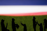 Boston Red Sox pitchers and staff cast shadows as they high-five in the bullpen before a baseball game against the Seattle Mariners, Sunday, March 31, 2024, in Seattle. (AP Photo/Lindsey Wasson)