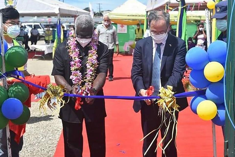 A photo taken on April 22 shows China's ambassador to the Solomon Islands Li Ming (R), and Solomons Prime Pinister Manasseh Sogavare (L) cutting a ribbon during the opening ceremony of a China-funded national stadium complex in Honiara. Source: AAP