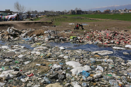 Syrian refugee children play near a garbage-filled cesspit at a makeshift settlement in Bar Elias town, in the Bekaa valley, Lebanon March 27, 2017. Picture taken March 27, 2017. REUTERS/Aziz Taher