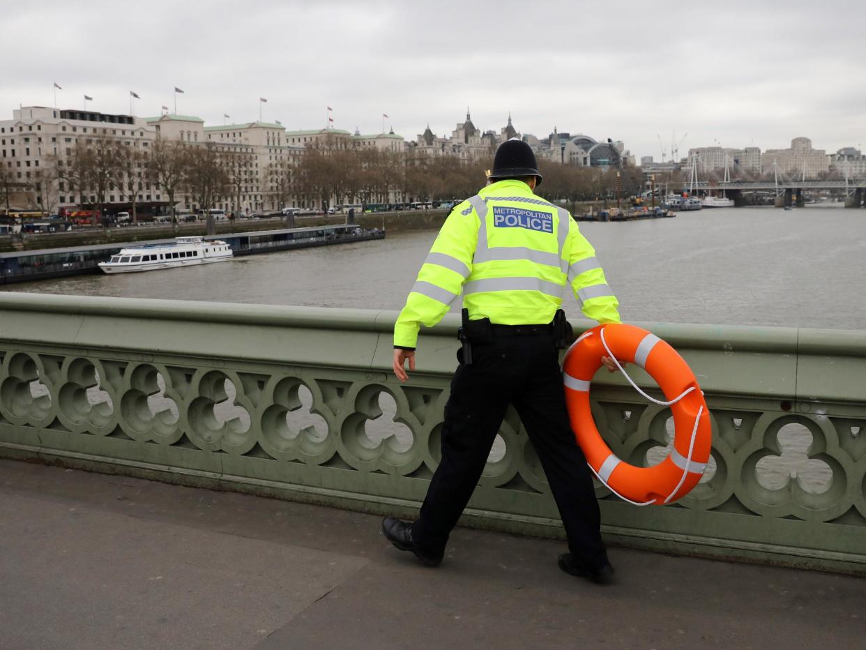 Police officer looks for a person thought to have fallen from Westminster Bridge: Getty