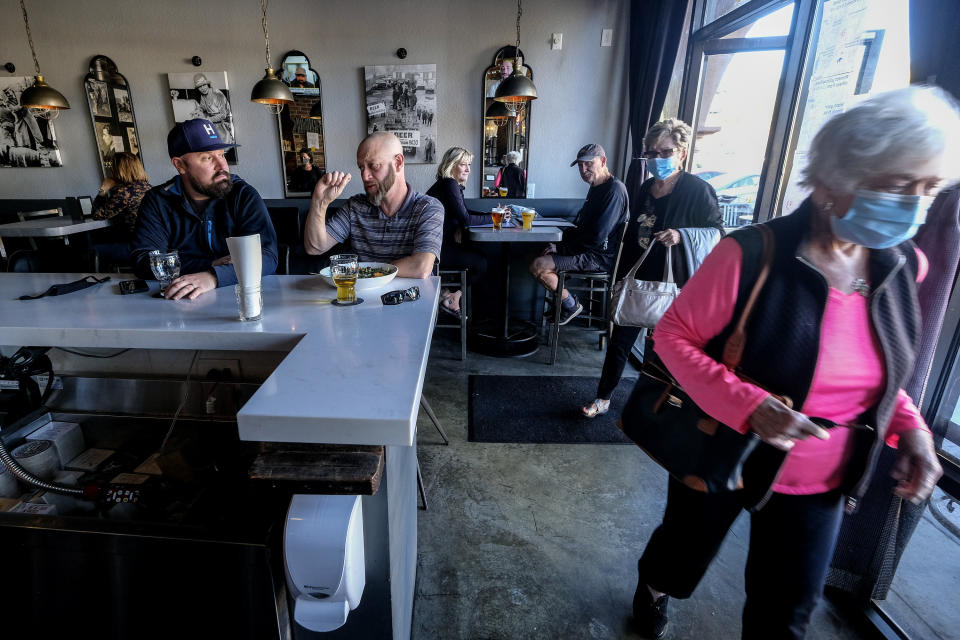 Patrons dine as customers wearing face masks walk into Notorious Burgers restaurant in Carlsbad, Calif., on Friday, Dec. 18, 2020. (AP Photo/Ringo H.W. Chiu)