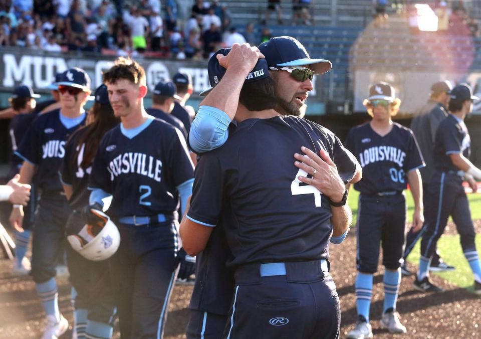 As the sun set in the background, Louisville head coach Brian Warner, face to camera, embraces Anthony Warner, 4, after being defeated in their DII regional final against Chardon at Thurman Munson Memorial Stadium on Friday, June 3, 2022.