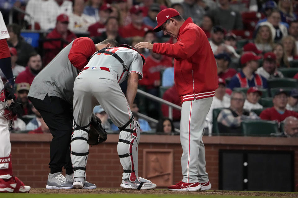 Philadelphia Phillies catcher J.T. Realmuto is checked on by Philadelphia Phillies manager Rob Thomson, right, after being injured during the seventh inning of a baseball game against the St. Louis Cardinals Tuesday, April 9, 2024, in St. Louis. Realmuto left the game. (AP Photo/Jeff Roberson)