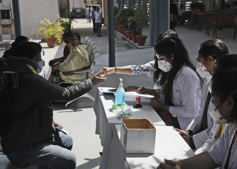 In this Thursday, March 12, 2020, photo, a doctor hands out free homeopathic pills in New Delhi, India. With no approved drugs for COVID-19, some people are turning to alternative medicines without evidence that they work. (AP Photo/Manish Swarup)