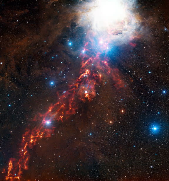 This dramatic new image of cosmic clouds in the constellation of Orion reveals what seems to be a fiery ribbon in the sky. The orange glow represents faint light coming from grains of cold interstellar dust, at wavelengths too long for human ey