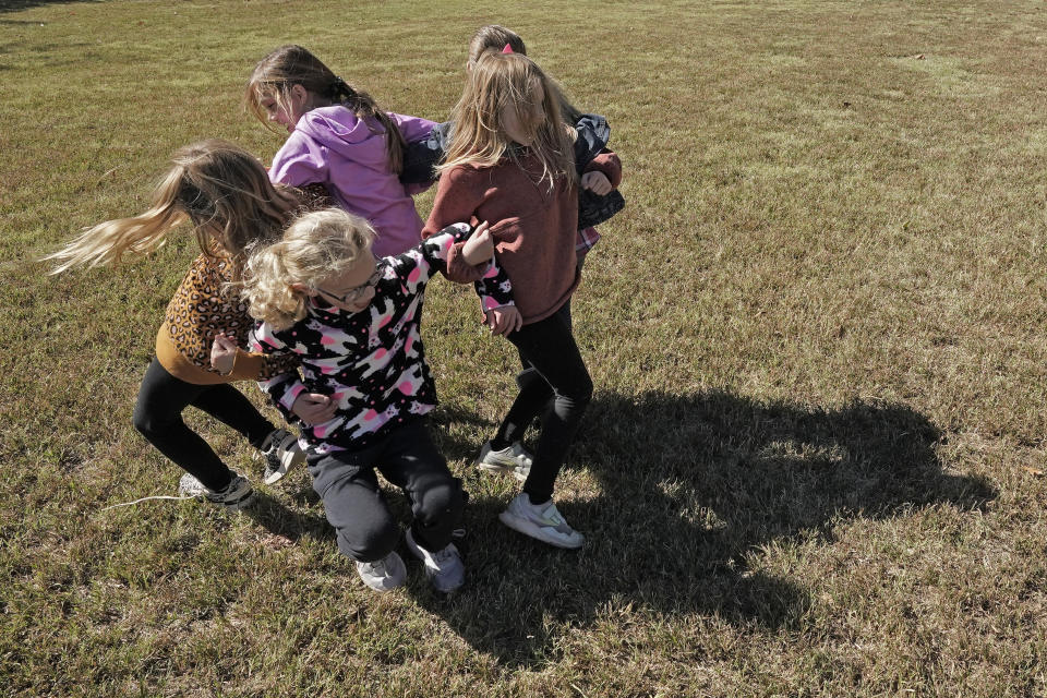 Third graders play Ring Around the Rosie during recess at Highland Elementary School in Columbus, Kan., on Monday, Oct. 17, 2022. Third graders in the tiny 900-student Columbus school district have fought to catch up on reading in the wake of COVID-19 disruptions. (AP Photo/Charlie Riedel)