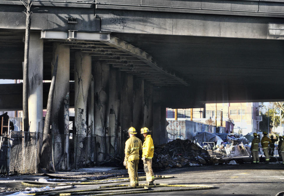 Damaged freeway columns are seen as Los Angeles firefighters mop up from a fire under Interstate 10 that severely damaged the freeway in an industrial zone near downtown Los Angeles, Saturday, Nov. 11, 2023. Authorities say firefighters have mostly extinguished a large blaze that burned trailers, cars and other things in storage lots beneath a major highway near downtown Los Angeles, forcing the temporary closure of the roadway. (AP Photo/Richard Vogel)