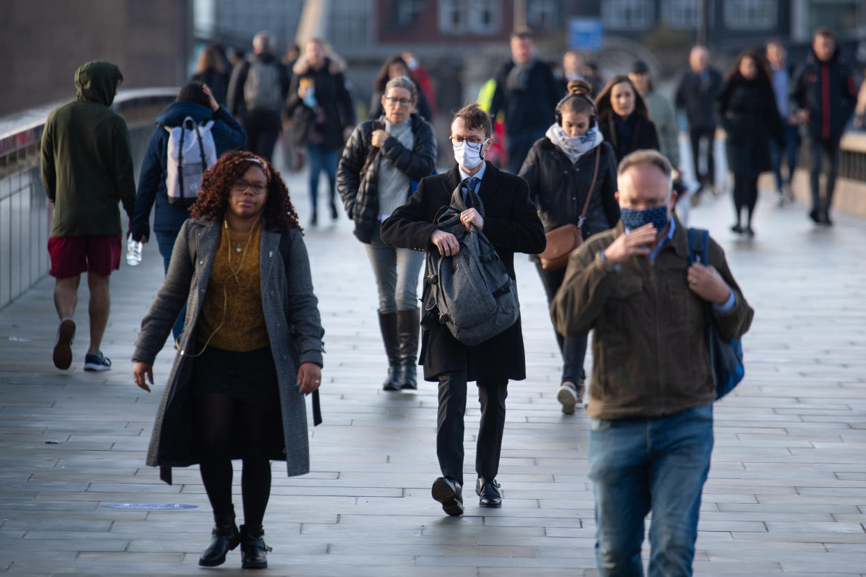 Commuters cross London Bridge, in central London, during morning rush hour after Prime Minister Boris Johnson set out a new three-tier system of alert levels for England following rising coronavirus cases and hospital admissions.