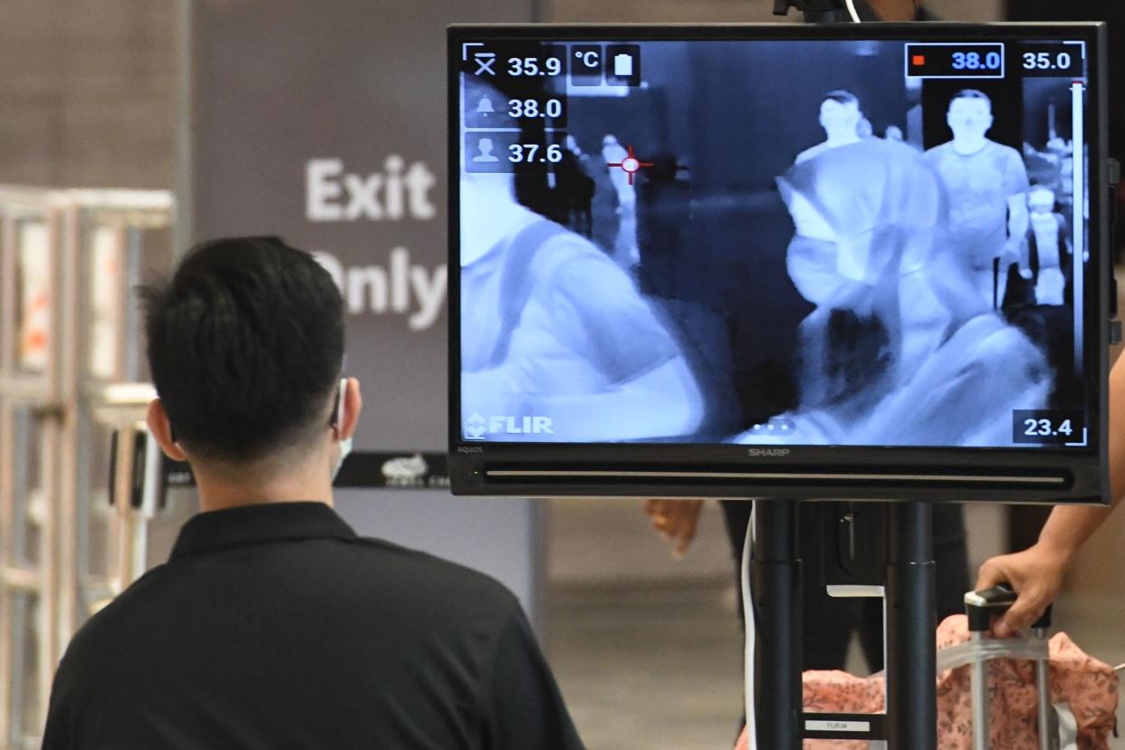A woman, wearing a protective facemask amid fears about the spread of the COVID-19 novel coronavirus, is seen on a monitor as she walks past a temperature screening check at Jewel Changi Airport in Singapore on February 27, 2020. (Photo by Roslan RAHMAN / AFP) (Photo by ROSLAN RAHMAN/AFP via Getty Images)