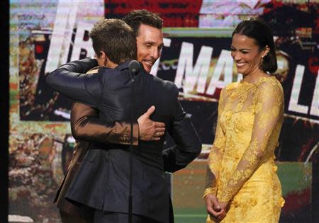 Matthew McConaughey, best male lead winner for his role in "Dallas Buyers Club"(2nd L) hugs presenter Jeremy Renner (L) as presenter Paula Patton (R) looks on as he accepts his award at the 2014 Film Independent Spirit Awards in Santa Monica, California March 1, 2014. REUTERS/Robert Galbraith