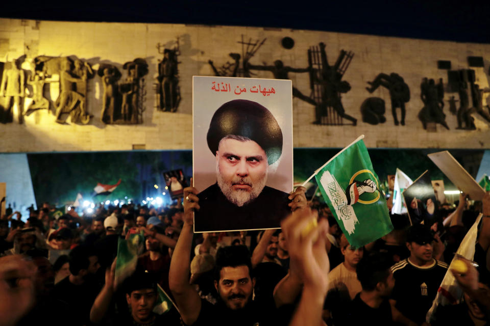 Followers of Shiite cleric Muqtada al-Sadr celebrate holding his posters, after the announcement of the results of the parliamentary elections in Tahrir Square, Baghdad, Iraq, Monday, Oct. 11, 2021. Iraq's Independent High Electoral Commission (IHEC) announced the parliamentary results of the November 10 vote which suggested that al-Sadr is the current front-runner with initial results coming from several Iraqi provinces. (AP Photo/Khalid Mohammed)