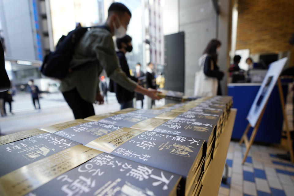 People pick up Japanese writer Haruki Murakami's new novel "The City and Its Uncertain Walls" on the first day for sale at Kinokuniya bookstore in Shinjuku district on early Thursday, April 13, 2023, in Tokyo. Murakami wrote a story of a walled city when he was fresh off his debut. More than four decades later, as a seasoned and acclaimed novelist, he gave it a new life as “The City and Its Uncertain Walls.” (AP Photo/Eugene Hoshiko)