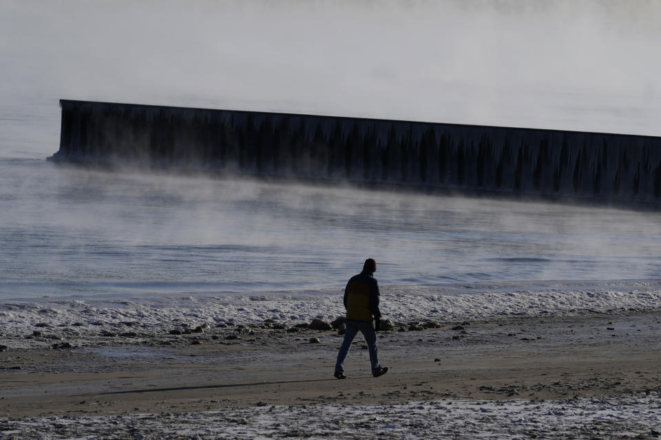 A man walks along the shore of Lake Michigan at the Lighthouse Beach in Evanston, Ill., Tuesday, Jan. 16, 2024. (AP Photo/Nam Y. Huh)