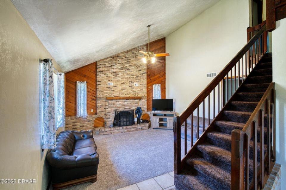 The interior of this two-story home offers vaulted ceilings and a brick fireplace in the spacious open living room.