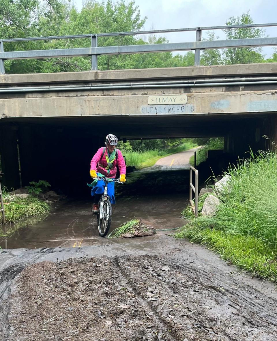 A cyclist steers around a grass and mud clod left on the Spring Creek Trail under Lemay Avenue on Monday after minor flooding over the weekend due to heavy rains Fort Collins.
