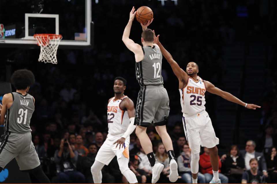 Phoenix Suns center Deandre Ayton (22) watches as Suns forward Mikal Bridges (25) defends Brooklyn Nets forward Joe Harris (12) who goes up for three points during the second half of an NBA basketball game, Monday, Feb. 3, 2020, in New York. The Nets defeated the Suns 119-97. (AP Photo/Kathy Willens)