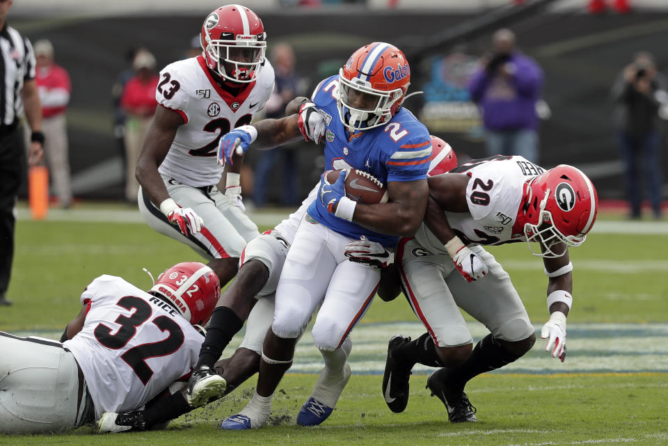 Florida running back Lamical Perine (2) is stopped after a short gain by the Georgia defense including linebacker Monty Rice (32) and defensive back J.R. Reed (20) during the first half of an NCAA college football game, Saturday, Nov. 2, 2019, in Jacksonville, Fla. (AP Photo/John Raoux)