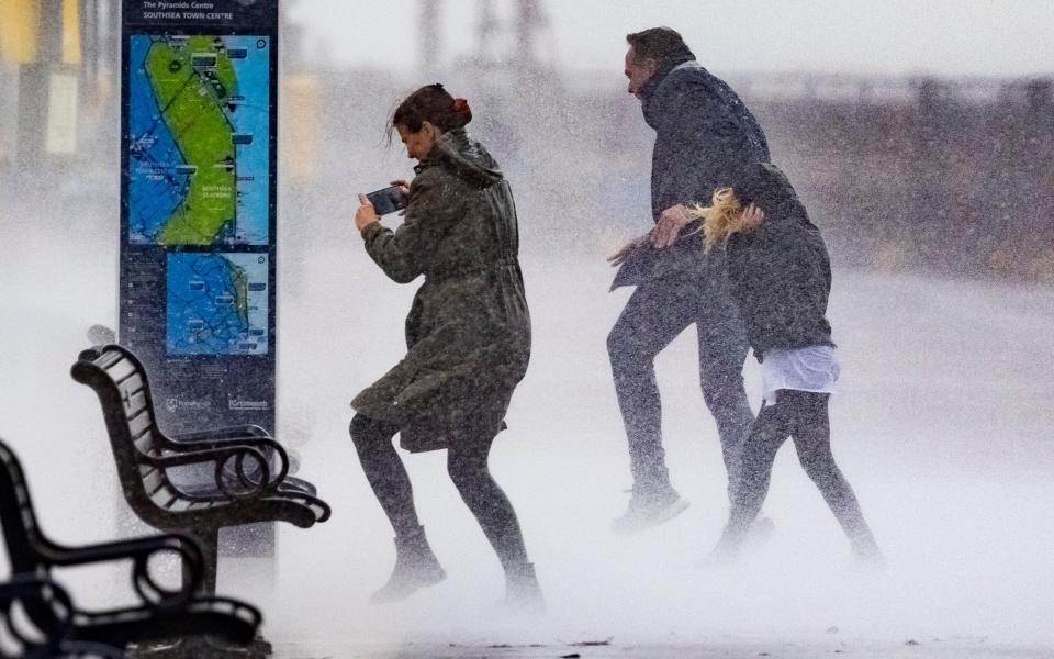 family get a soaking as waves crash over the sea wall at Southsea in Portsmouth