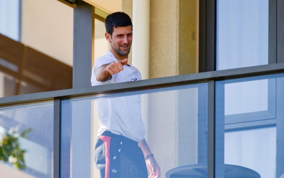 Men's world number one tennis player Novak Djokovic of Serbia gestures from his hotel balcony in Adelaide on January 18, 2021, one of the locations where players have quarantined for two weeks upon their arrival ahead of the Australian Open tennis tournament in Melbourne - AFP/BRENTON EDWARDS 