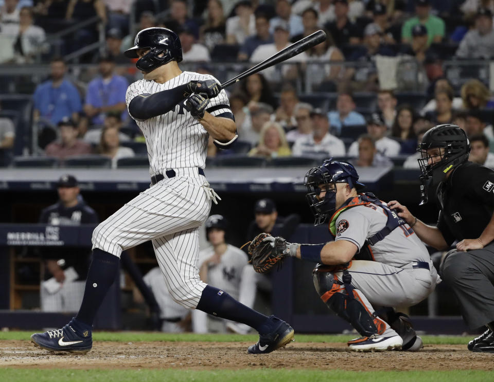 New York Yankees' Giancarlo Stanton follows through on a two-run single during the seventh inning of a baseball game as Houston Astros' catcher Max Stassi watches, Saturday, June 22, 2019, in New York. (AP Photo/Frank Franklin II)