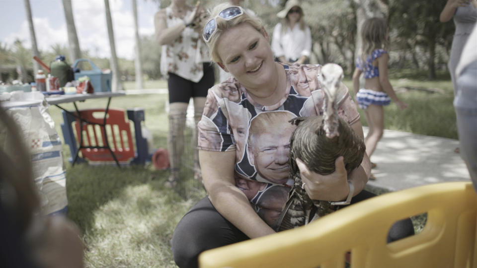 A woman wearing a Donald Trump shirt holds a turkey during a visit to a petting zoo at The Hollow in Venice, Fla., on July 31, 2022. The 10-acre site is at times a children’s playland, wedding venue, far-right organizing space and weapons training ground. (Richard Rowley/Frontline via AP)