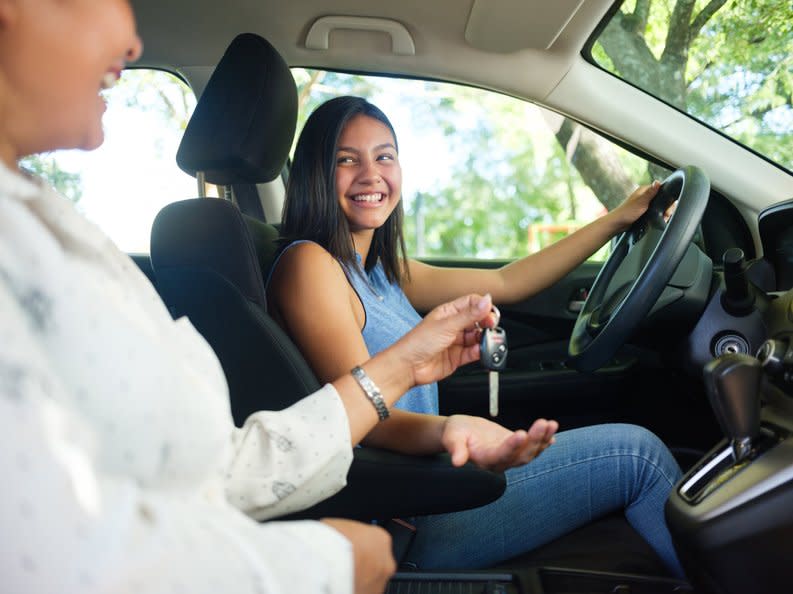 Teen girl in the driver's seat of a vehicle with a parent sitting passenger.