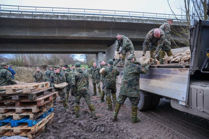 German Armed Forces (Bundeswehr) soldiers load sandbags from a truck to secure a dyke on the Helme in the flood areas in Saxony-Anhalt Jan Woitas/dpa