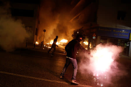 A masked demonstrator holds a flare as others throw petrol bombs to riot police during a rally marking four years since the fatal stabbing of Greek anti-fascism rapper Pavlos Fyssas by a supporter of the ultranationalist Golden Dawn party in Athens, Greece, September 16, 2017. REUTERS/Alkis Konstantinidis