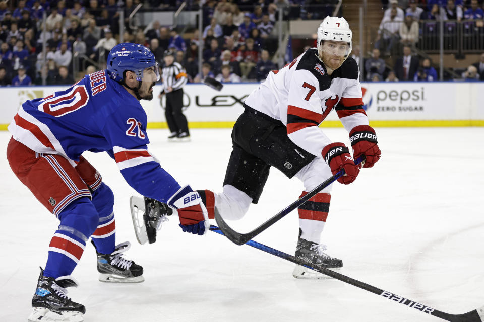 New Jersey Devils defenseman Dougie Hamilton (7) clears the puck past New York Rangers left wing Chris Kreider during the first period of Game 3 of the team's NHL hockey Stanley Cup first-round playoff series Saturday, April 22, 2023, in New York. (AP Photo/Adam Hunger)