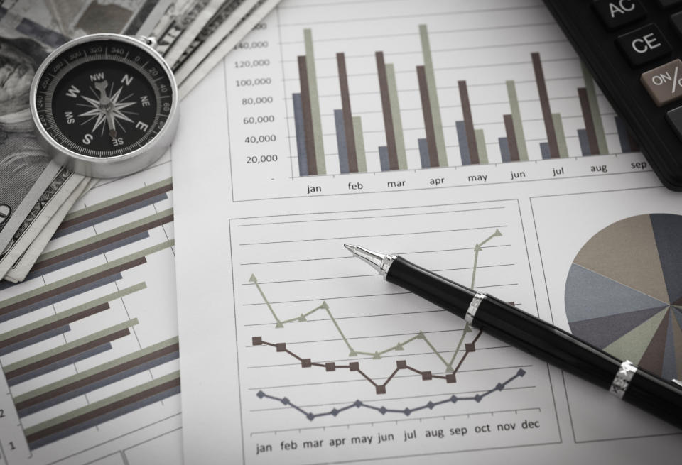 Pen on diagram chart and graphs business report with money, compass, calculator on desk of financial advisor.  Accounting and Financial Planning Concept