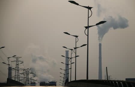 Smoke rises from chimneys of a steel plant next to a viaduct on a hazy day in Tangshan, Hebei province February 18, 2014. REUTERS/Petar Kujundzic