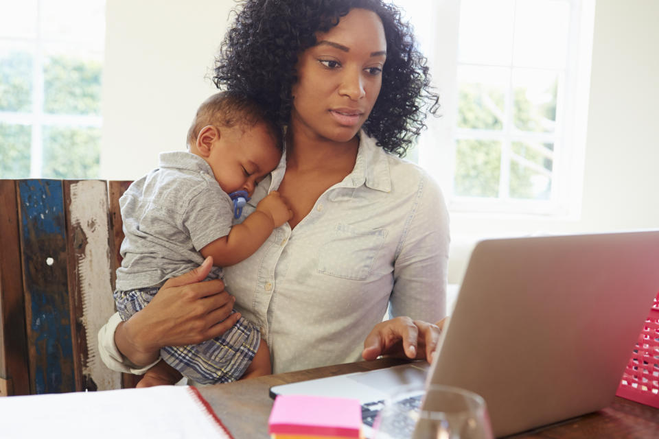 mom working on her computer while holding her baby