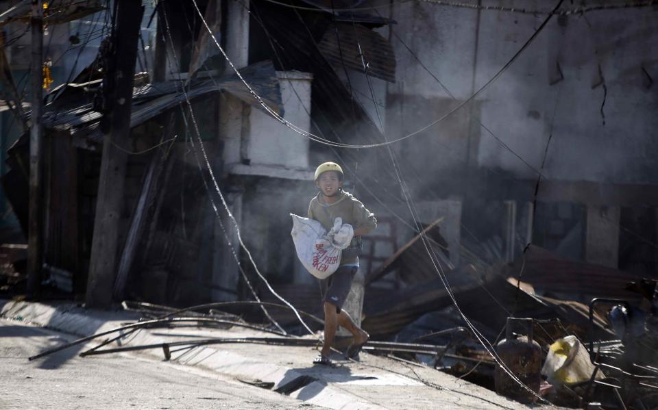 A resident carries his piglet inside a sack that survived a fire caused by fighting between government soldiers and Muslim rebels from the Moro National Liberation Front (MNLF) in Zamboanga city in southern Philippines