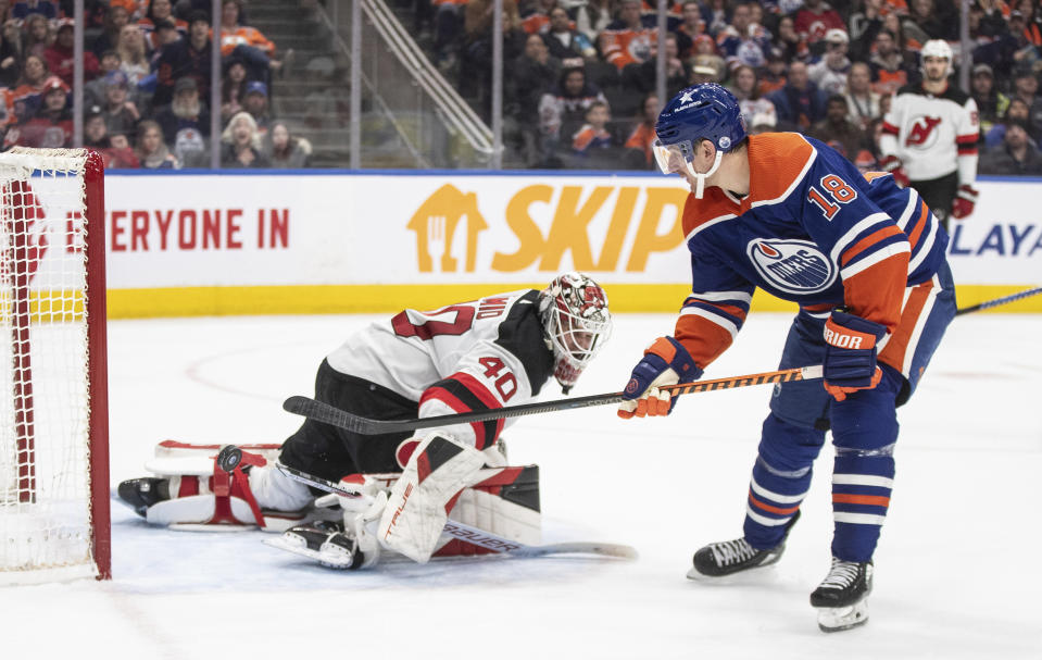 New Jersey Devils goalie Akira Schmid (40) makes a save against Edmonton Oilers' Zach Hyman (18) during second-period NHL hockey game action in Edmonton, Alberta, Sunday, Dec. 10, 2023. (Jason Franson/The Canadian Press via AP)