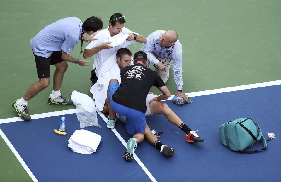 FILE - Jack Sock is tended to by medical personnel after collapsing on the court during play against Ruben Bemelmans, of Belgium, during the second round of the U.S. Open tennis tournament, Sept. 3, 2015, in New York. An Associated Press analysis shows the average high temperatures during the U.S. Open and the three other Grand Slam tennis tournaments steadily have grown hotter and more dangerous in recent decades. (AP Photo/Adam Hunger, File)