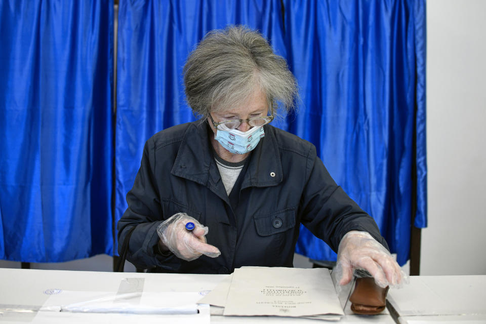 A woman wearing a mask to protect against COVID-19 infection prepares to cast her vote in Bucharest, Romania, Sunday, Sept. 27, 2020. Some 19 million registered voters are choosing local officials, council presidents and mayors to fill more than 43,000 positions across the European Union nation. (AP Photo/Andreea Alexandru)