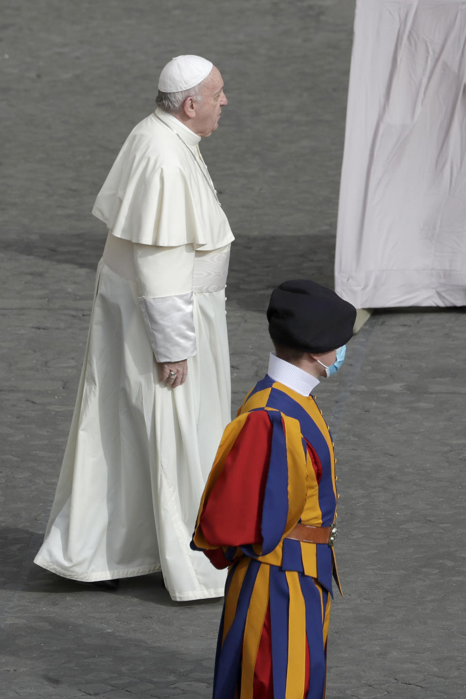 FILE - In this Sept. 2, 2020 file photo, Pope Francis walks by a Vatican Swiss guard wearing a face mask to prevent the spread of COVID-19 as he arrives at the San Damaso courtyard for his general audience, the first with faithful since February when the coronavirus outbreak broke out, at the Vatican. On Monday, Oct. 12, 2020, the Vatican said in a statement that four Swiss Guards have tested positive for the coronavirus, as the surge in infections in surrounding Italy enters the Vatican walls. (AP Photo/Andrew Medichini, file)