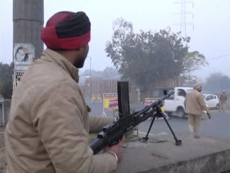 A policeman stands guard with a gun as vehicles pass by, following an attack on an Indian Air Force base in Pathankot on Saturday, near the border with Pakistan, in Ludhiana, Punjab, in this still frame taken from video, January 2, 2016. REUTERS/ANI/via Reuters/Files