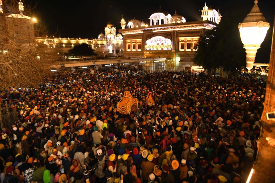 Sikh devotees spray perfume and shower flower petals on the Palki Sahib, which carries the Guru Granth Sahib (Sikh holy books) to mark the "Hola Mohalla" festival during a procession from the Golden Temple to Sri Akal Takhat Sahib in Amritsar, northern India, on March 10, 2020. Hola Mohalla is a three-day Sikh festival, in which Nihang Sikh "warriors" perform Gatka (mock encounters with real weapons), tent pegging and bareback horse-riding, following the Hindu festival of Holi in Amritsar on March 10, 2020.